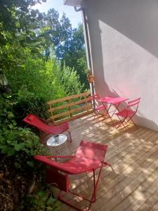 four red chairs and a table on a deck at Le nid douillet in Aydat