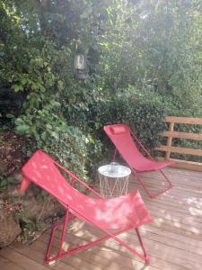 two red chairs sitting on a wooden deck at Le nid douillet in Aydat +4 photos