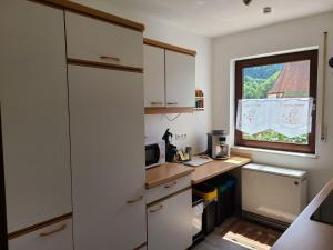 a small kitchen with white cabinets and a window at Ferienwohnung am Südhang in Gernsbach