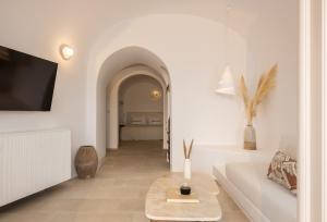 a living room with a couch and a tv on a wall at Canaves Ena - Small Luxury Hotels of the World in Oia
