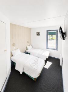 a room with three beds and a window at Hôtel Gex in Gex
