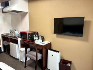 a room with a desk with a microwave and a tv at ITOSHI Kyoto Stay 京都天神401 in Kyoto