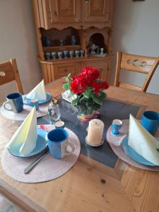 a wooden table with plates and a vase of red flowers at Ferienwohnung Schneifelsicht in Auw