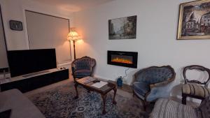 a living room with a tv and a couch and chairs at The Piddington Top in Mount Victoria