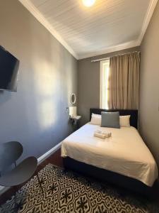 a bedroom with a bed and a chair and a window at CapePod Sea Point in Cape Town