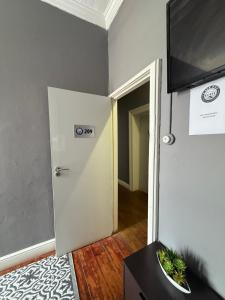 a room with a white door and a television on a wall at CapePod Sea Point in Cape Town