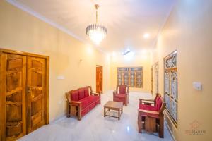 a living room with red chairs and a chandelier at Zen Nallur in Jaffna