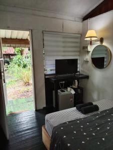 a bedroom with a bed and a desk and a television at Blissful Garden Chalet Langkawi in Pantai Cenang