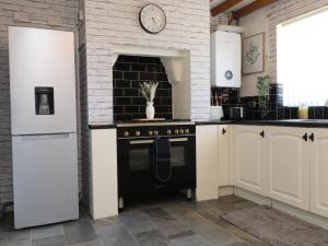 a kitchen with a stove and a clock on the wall at 31 Ffordd Y Maer in Pwllheli