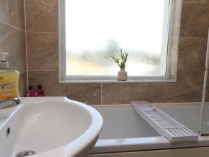 a bathroom with a white sink and a window at 31 Ffordd Y Maer in Pwllheli +14 photos