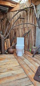 a bathroom with a toilet on a wooden floor at Hidden Cabin in Iringa