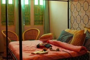 a bedroom with a bed with orange sheets and chairs at DanCenter Kolpol by CheckIn Udaipur in Udaipur