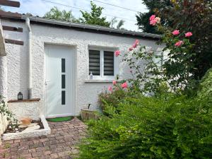 a white house with a white door and some pink roses at Cottage 3 étoiles avec jardin & parking, proche Paris et Disneyland in Chelles