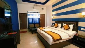 a hotel room with a bed and a television at Hotel Bhagirathi in Tehri-Garhwāl