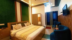 a bedroom with a bed and a chair and a television at Hotel Bhagirathi in Tehri-Garhwāl
