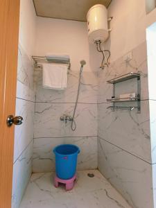 a bathroom with a shower with a blue bucket in it at Hotel Bhagirathi in Tehri-Garhwāl +5 photos