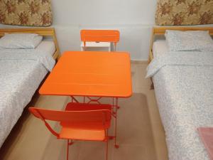 an orange table and chair in a room with two beds at Christos in Asvestokhórion