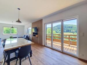 a living room with a table and chairs and a balcony at Maison 8 pers rénovée nature, calme, proche Vosges in Colroy-la-Roche