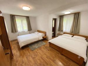 two beds in a room with wooden floors and windows at Pensiunea Barsan in Vişeu de Sus +13 photos