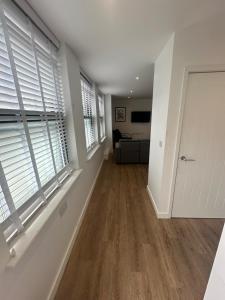 an empty living room with white walls and windows at The Apollo Apartments in Saint Neots