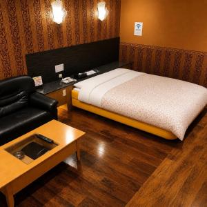 a bedroom with a bed and a couch and a table at 名古屋北区のホテルコアラ in Tsujichō
