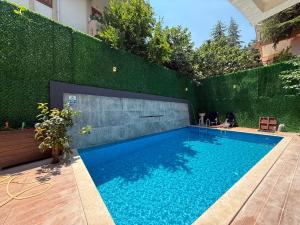 a swimming pool in front of a green hedge at Luxury villa in mountain in Geyikbayırı