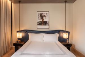 a bedroom with a large white bed with two lamps at Thompson Rome, By Hyatt in Rome