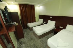 a hotel room with two beds and a flat screen tv at فندق فيصل الصفوة in Al Khansāk