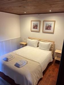 a bedroom with a white bed with two towels on it at Bungalow Refúgio do Pezo T1 in Melgaço +3 photos
