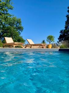 a pool of blue water with some chairs and tables at La Grange de Verseilles in Saint-Étienne-de-Vicq
