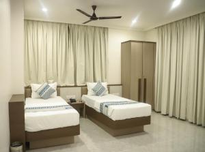 a bedroom with two beds and a ceiling fan at Madhu's Palace in Amarnāth +97 photos