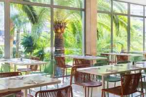 a restaurant with tables and chairs and a palm tree at SOL by Meliá Barbados in Magaluf