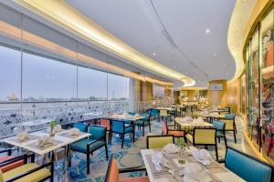 a restaurant with tables and chairs and a large window at Hotel Ciputra Cibubur managed by Swiss-Belhotel International in Cibubur