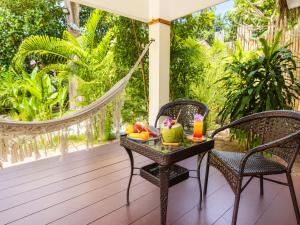 a porch with a table with fruit and a hammock at Ocean Vibes Resort in Thong Sala