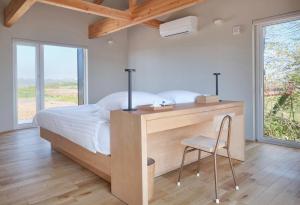 a bedroom with a bed and a desk with a chair at Adagio Retreat Tokachidake in Biei