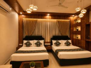 a bedroom with two beds and a table at Hotel Baba Deluxe near New Delhi Railway Station and City Center -By RCG Hotels in New Delhi