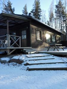 una cabaña de madera en la nieve en frente en Strandbo en Förby