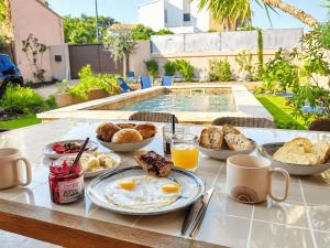 a breakfast table with eggs and bread and drinks at Villa Mezzanotte Le Brusc 80m de la mer - Climatisation-Piscine-Parking in Six-Fours-les-Plages