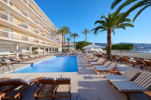 ein Resort-Pool mit Liegestühlen und Palmen in der Unterkunft Zel Mallorca in Palmanova