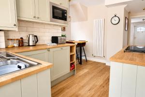 a kitchen with white cabinets and a sink at Appletree Cottage in Wells +15 photos