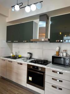 a kitchen with a stove and a microwave at Sol's M2 White Modern Apartments in Tbilisi City