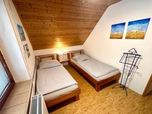 two beds in a small room with wooden ceilings at Ubytko Ivko in Letohrad