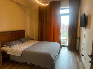 a bedroom with a bed and a large window at Sol's M2 White Modern Apartments in Tbilisi City