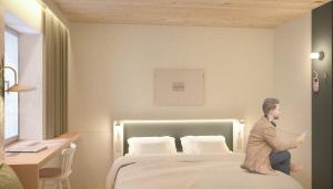 un uomo seduto su un letto in una stanza d'albergo di MEADOW Gronau by Hackmann a Gronau