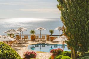 a pool with tables and umbrellas and the ocean at Il Pellicano in Porto Ercole
