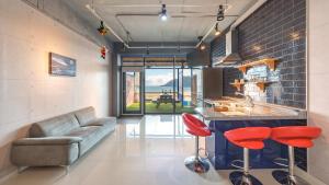 a living room with a couch and a kitchen with red stools at Goseong CNBLUE Oceanview Pension in Goseong