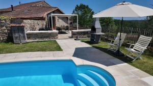 a blue swimming pool with an umbrella and a house at Domaine de Bellac - Le Triangle in Roussines