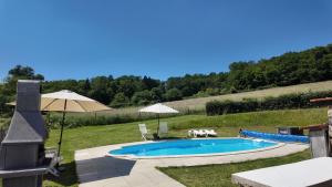 a swimming pool in a yard with an umbrella at Domaine de Bellac - Le Triangle in Roussines