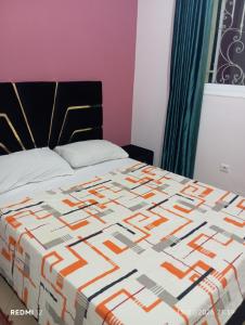 a bed with an orange and white quilt on it at ALmas apparemment in Ifrane