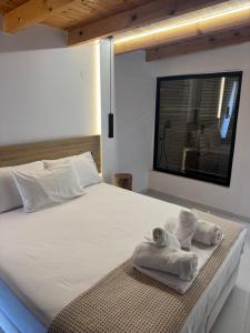a bedroom with a white bed with towels on it at 44 suites Lygia in Paralia Vrachou